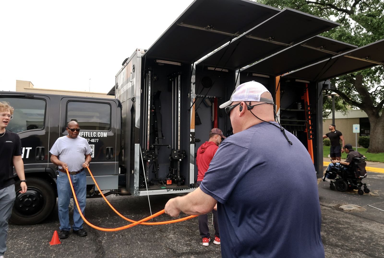 Participants using adaptive training ropes in front of the mobile gym